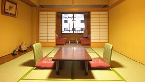 A traditional Japanese tatami room with a low wooden table, two patterned chairs, and a view of a building through a shoji screen. - Hotel Sanraku (Yamanouchi)
