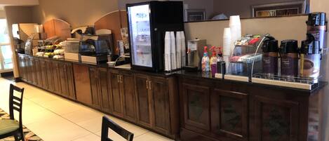 A hotel reception area with a counter, coffee machines, and a hot water station.
