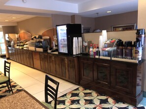 A hotel reception area with a counter, coffee machines, and a hot water station.