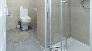 Een moderne badkamer met een douchecabine van glas, een toilet en een wastafel.