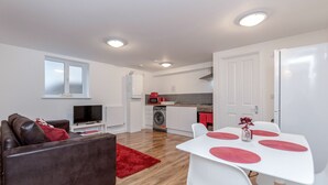 Een knus woongedeelte met een bank, televisie, eettafel en kitchenette.