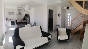 Un salon moderne avec un canapé noir et blanc, une petite table et un escalier menant à un niveau supérieur.