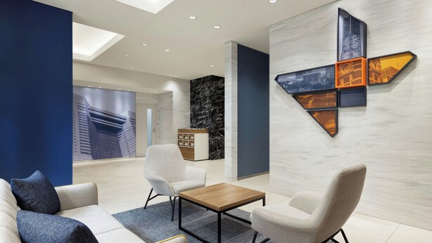 A modern lounge area with a sofa, chairs, a coffee table, and a cityscape mural on the wall. - Four Points Flex by Sheraton Yokohama West (Yokohama)
