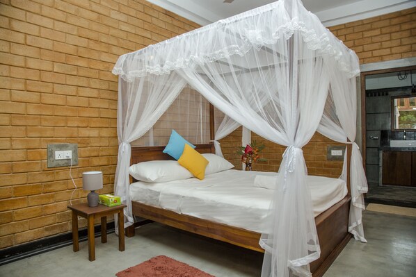 A bedroom with a wooden bed, a nightstand, a lamp, and a brick wall.