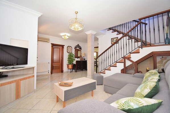 A living room with a television, sofa, coffee table, and staircase.