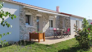 A stone facade building with a tiled roof, a wooden bench with plants, and a table with chairs in the foreground. - YOUR HOLIDAY AT  SABLES D'OLONNE THE MOST BEAUTIFUL BEACH ON THE COTE DE LUMIERE (Le Château-d'Olonne)