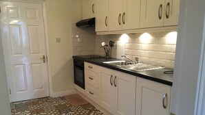 A kitchen with white cabinets, a black countertop, and a patterned tile floor. - House located in a private maintained estate. (Tralee)