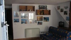 A living room with a sofa, a radiator, and wall-mounted shelves with pictures.