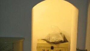 A room with a wooden dresser, a floral cabinet, and a lamp.