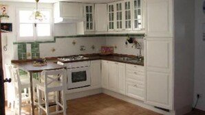 A kitchen with white cabinets, a stove, and a dining area with chairs.