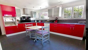 Una cocina moderna con armarios de color rojo y blanco, una mesa de comedor con sillas y un ventanal que proporciona luz natural.