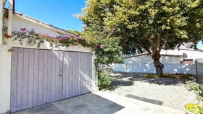 Stroll through the garden surrounded by lush plants and flowers, with a large tree providing shade.