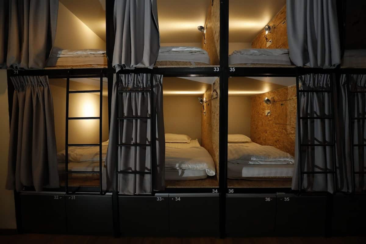 A dormitory-style room with bunk beds, numbered from 31 to 36, and curtains on each window.