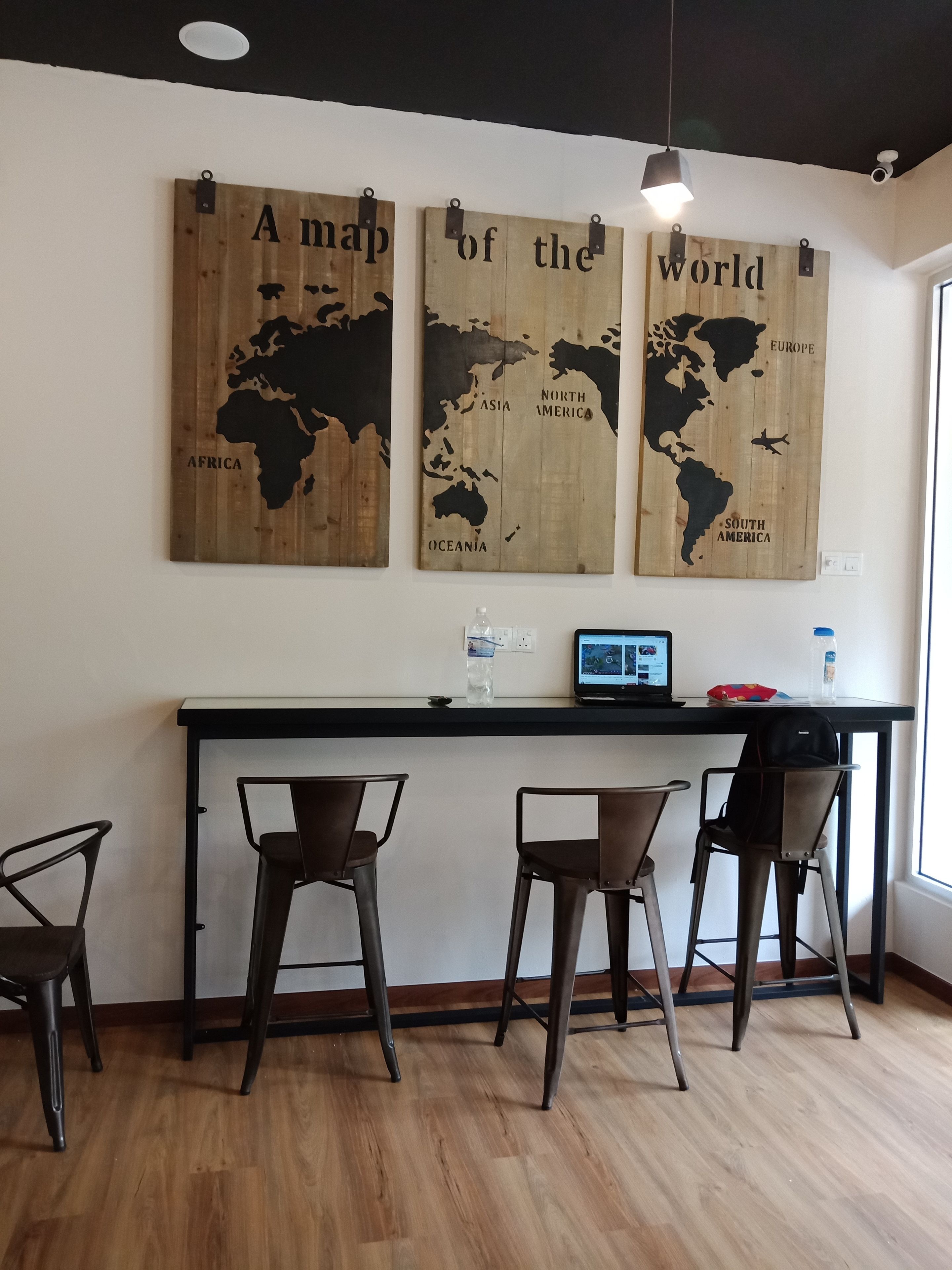 A modern kitchen with a wooden countertop, two bar stools, and a world map mural on the wall.