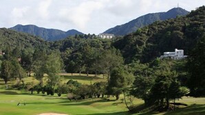 Un campo de golf con un club de campo y montañas al fondo.