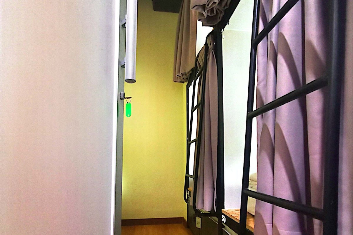A narrow hallway with bunk beds, wooden flooring, and a white wall with a door.