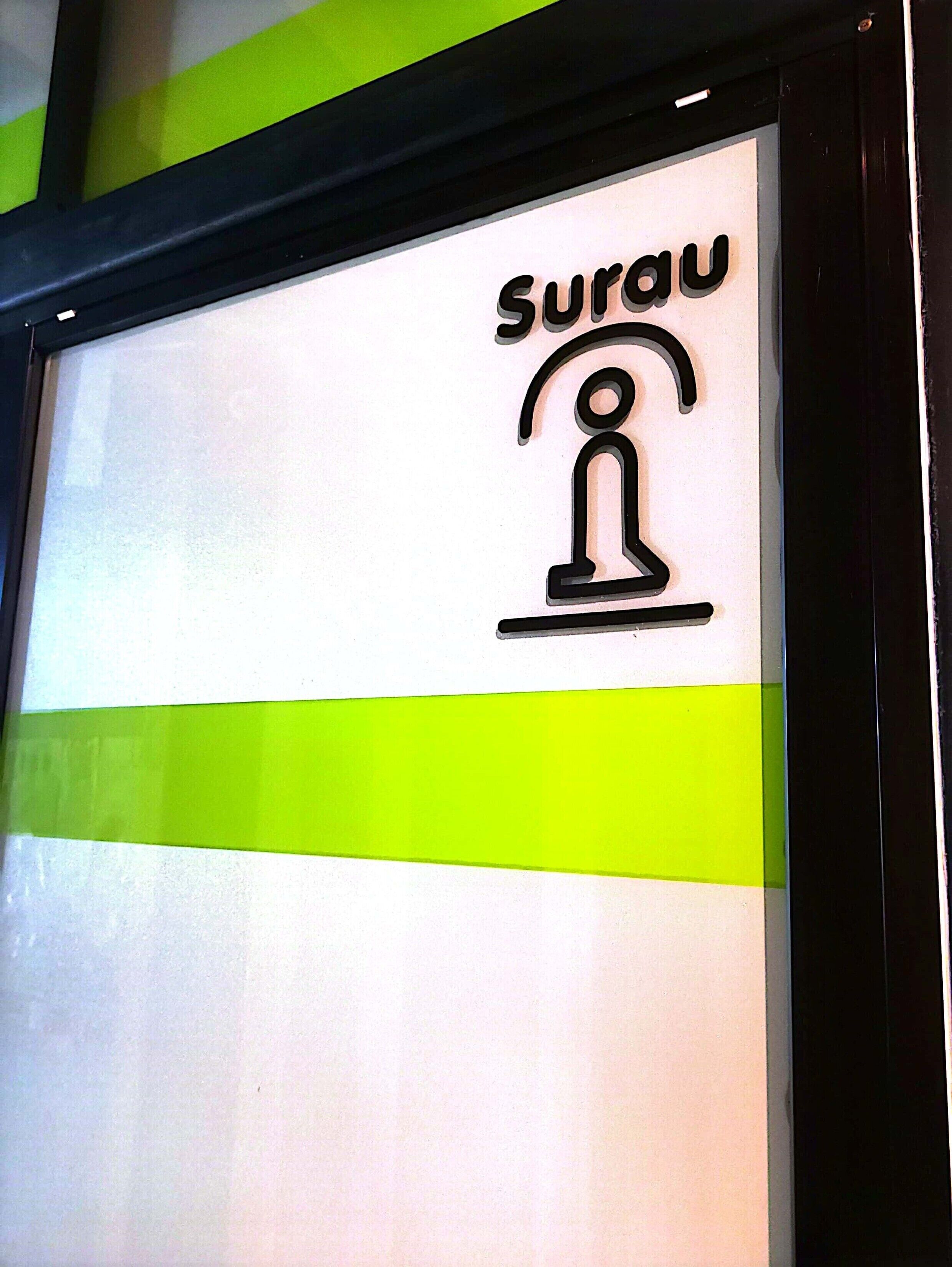 A sign with the word "Surau" and a symbol of a person standing on a platform.