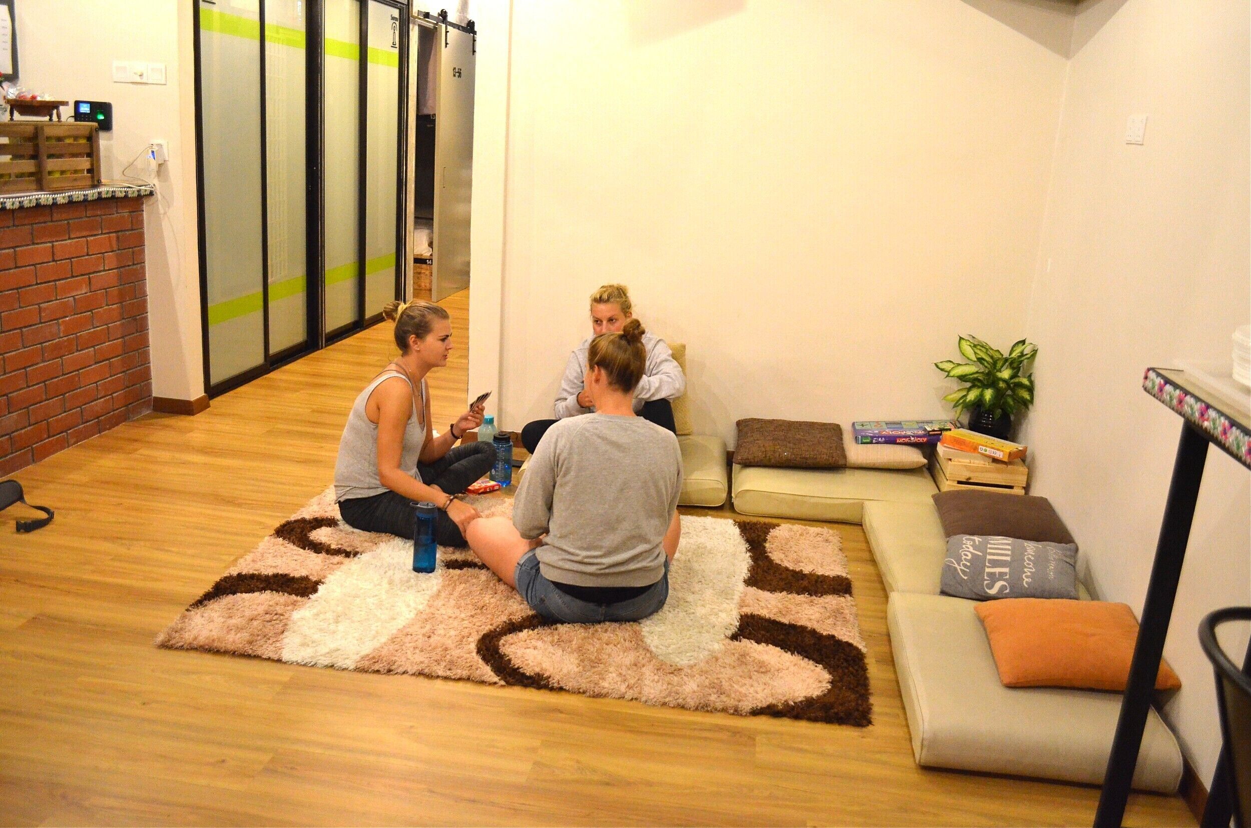 A room with a wooden floor, a patterned rug, a sofa, and a small table with a plant.