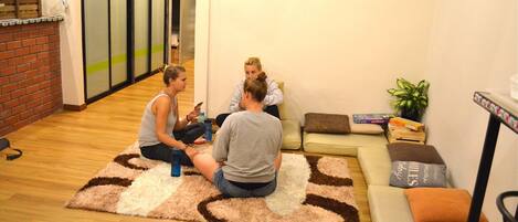 A room with a wooden floor, a patterned rug, a sofa, and a small table with a plant.