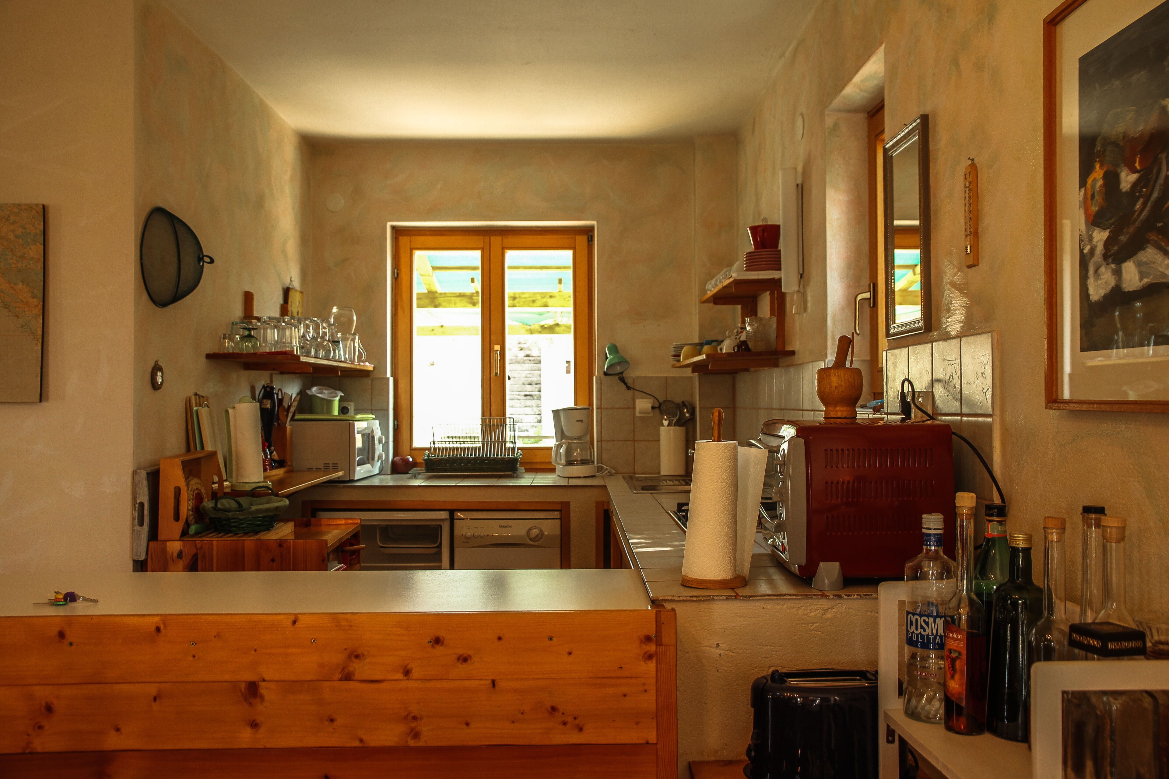 A kitchen with wooden cabinets, a sink, and a window with a view of a garden.