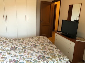 Ein Schlafzimmer mit einem Bett, einem Schminktisch, einem Fernseher und einem Kleiderschrank.