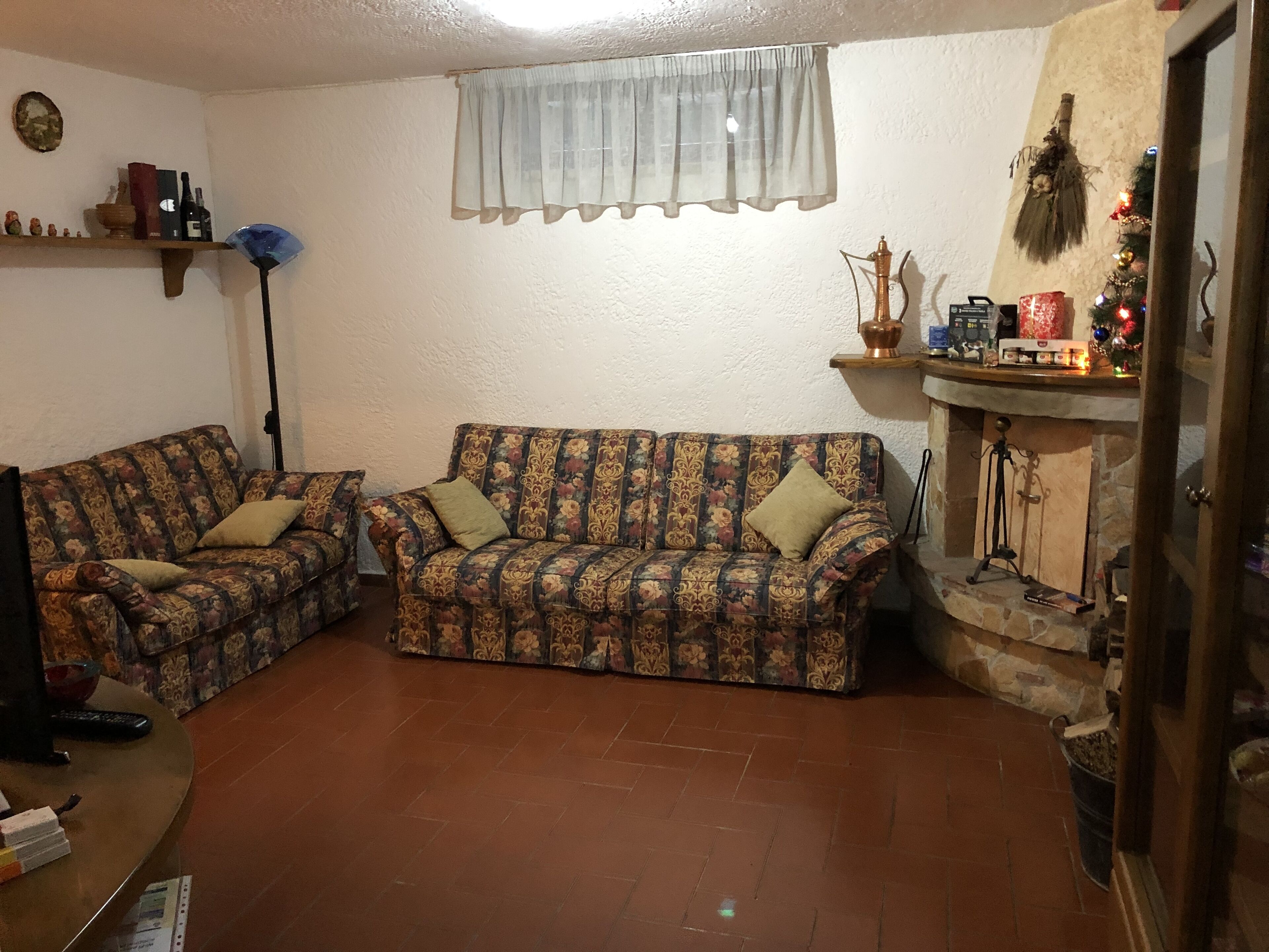 Una sala de estar con dos sofás estampados, una chimenea y un pequeño árbol de Navidad.