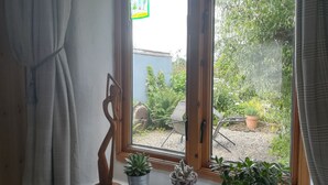 Et værelse med et vindue, gardin og udsigt til en have.