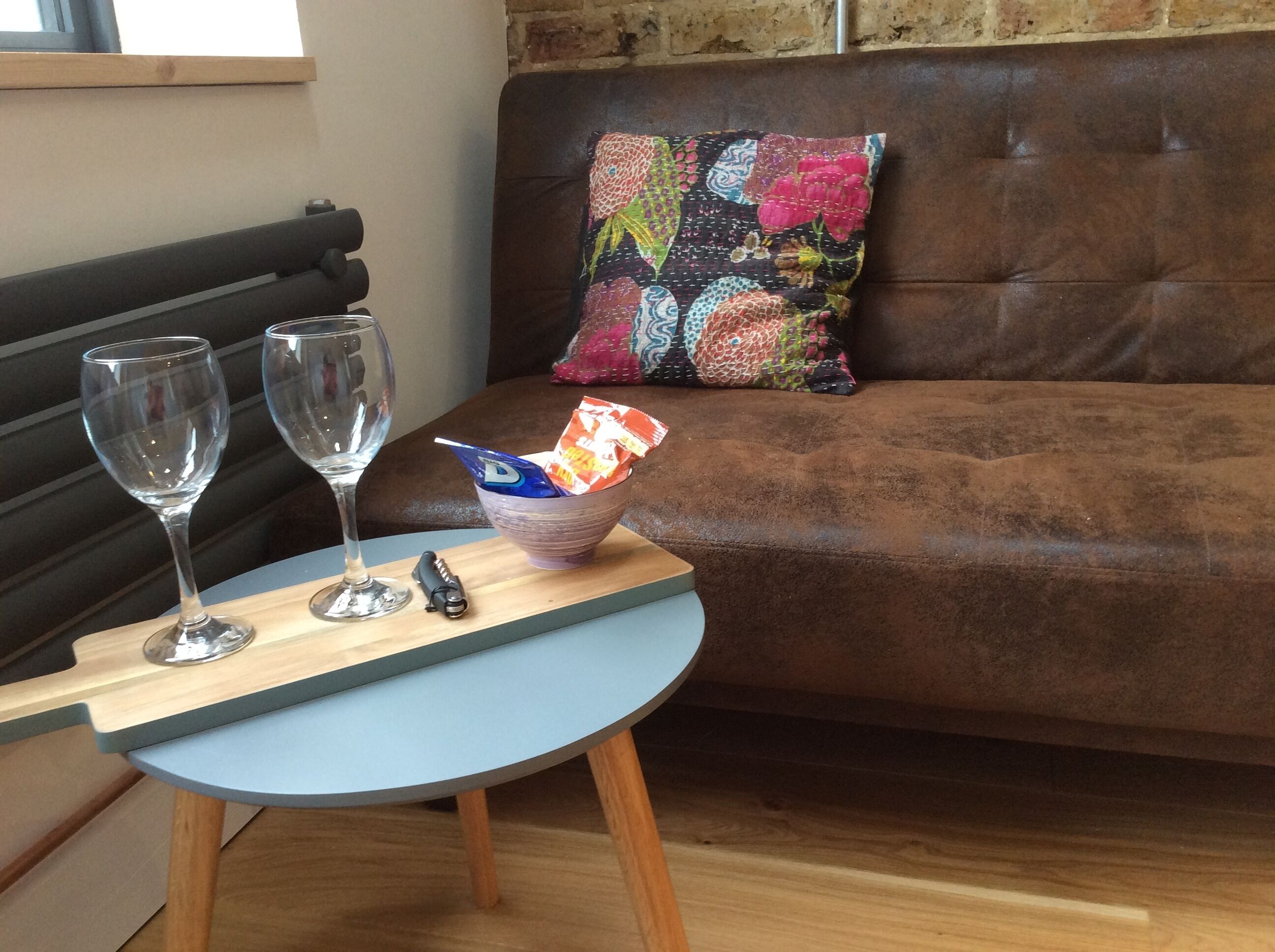 A small round table with two wine glasses and a bowl containing snacks.