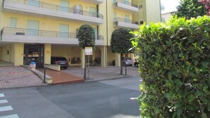Ein mehrgeschossiges Gebäude mit Balkonen, einem Parkplatz und einer Fußgängerquerung.