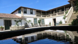A courtyard with a water feature, white buildings with green window frames, and a staircase leading to an upper level.