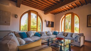 A spacious living room with a large sectional sofa, a glass coffee table, and arched windows allowing natural light. - EXCLUSIVE CHIANTI VILLA SPECTACULAR POOL TENNIS COURT 15 MIN TOFLORENCE   (IMPRUNETA)
