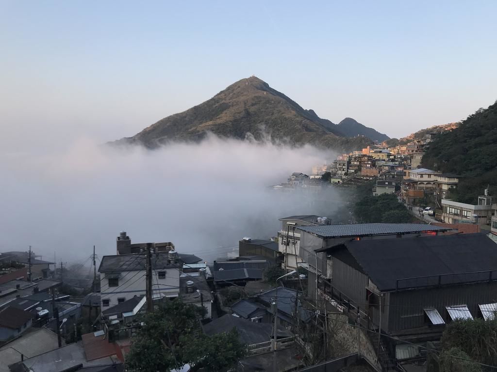 Eine Küstenstadt mit Häusern am Fuß eines Berges, umgeben von Nebel.