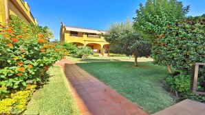 A yellow building with a tiled pathway leading to a covered area. - VACAY L'Escala - Apartamento Tropicana (L'ESCALA)