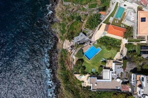 An aerial view of a coastal property with a swimming pool, a tennis court, and a small garden area. - Eufemia´s Villa - Funchal Seaside Villas (Funchal)