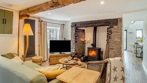 Una sala de estar acogedora con chimenea de piedra, televisor y comedor con mesa y sillas.