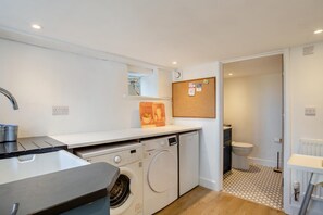 Een kleine keuken met een wasmachine, een spoelbak en een klein aanrecht.