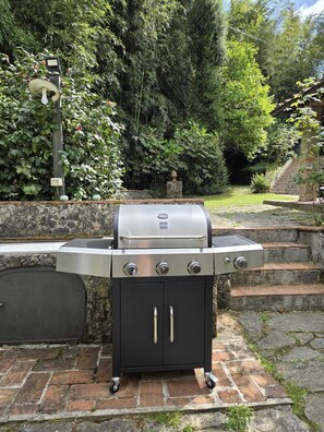 Un barbecue au gaz portatif doté d’un écran numérique, d’un meuble latéral avec deux tiroirs et d’un mur en pierres en arrière-plan.