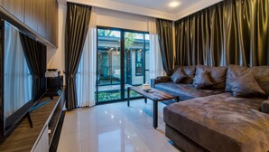A modern living room with a leather sofa, a flat-screen TV, and a sliding glass door leading to a balcony. - Sierra Pool Villa Hua Hin 102 (Hua Hin)