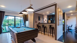 A pool table in a modern room with a bar area and a view of greenery outside. - Sierra Pool Villa Hua Hin 102 (Hua Hin)