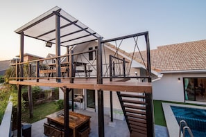 Una casa moderna en construcción con terraza de madera, piscina y zona de patio.