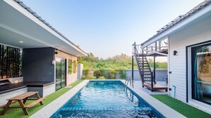 A modern outdoor swimming pool with a wooden deck and a staircase leading to a covered area. - Sierra Pool Villa Hua Hin 102 (Hua Hin)