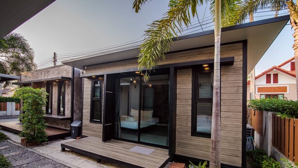 A modern house with a wooden exterior, large glass windows, and a small deck area. - Sierra Pool Villa Hua Hin 102 (Hua Hin)