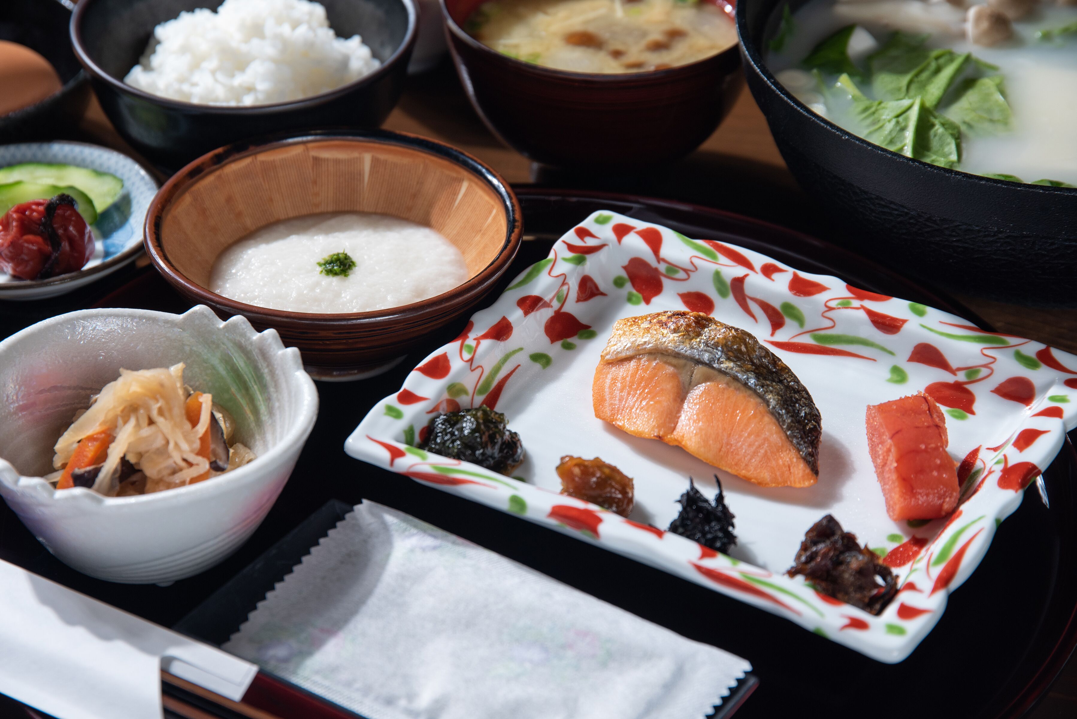 A variety of dishes including salmon, rice, and soup, arranged on a table.