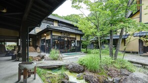 Ein traditionelles japanisches Gebäude mit einem Steingefäß und einer hölzernen Sitzgruppe im Vordergrund.