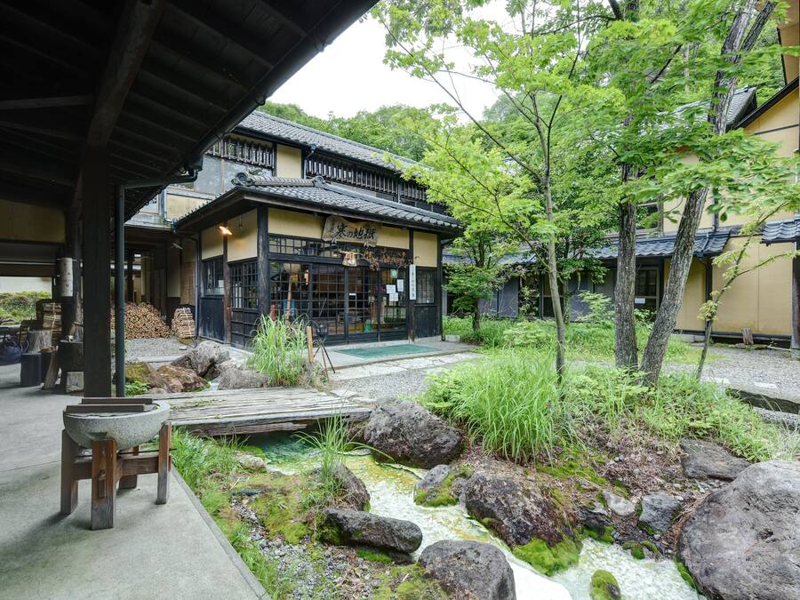 A traditional Japanese building with a stone basin and wooden seating area in the foreground.