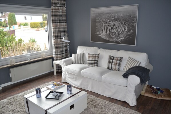 A living room with a white sofa, a coffee table, and a radiator.