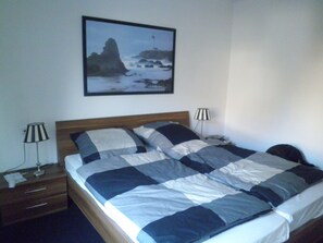 A bedroom with a bed, two bedside tables, a lamp, and a framed picture on the wall.