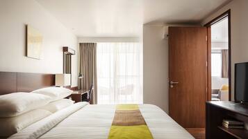 Una habitación de hotel con cama, escritorio, silla, televisor y puerta.