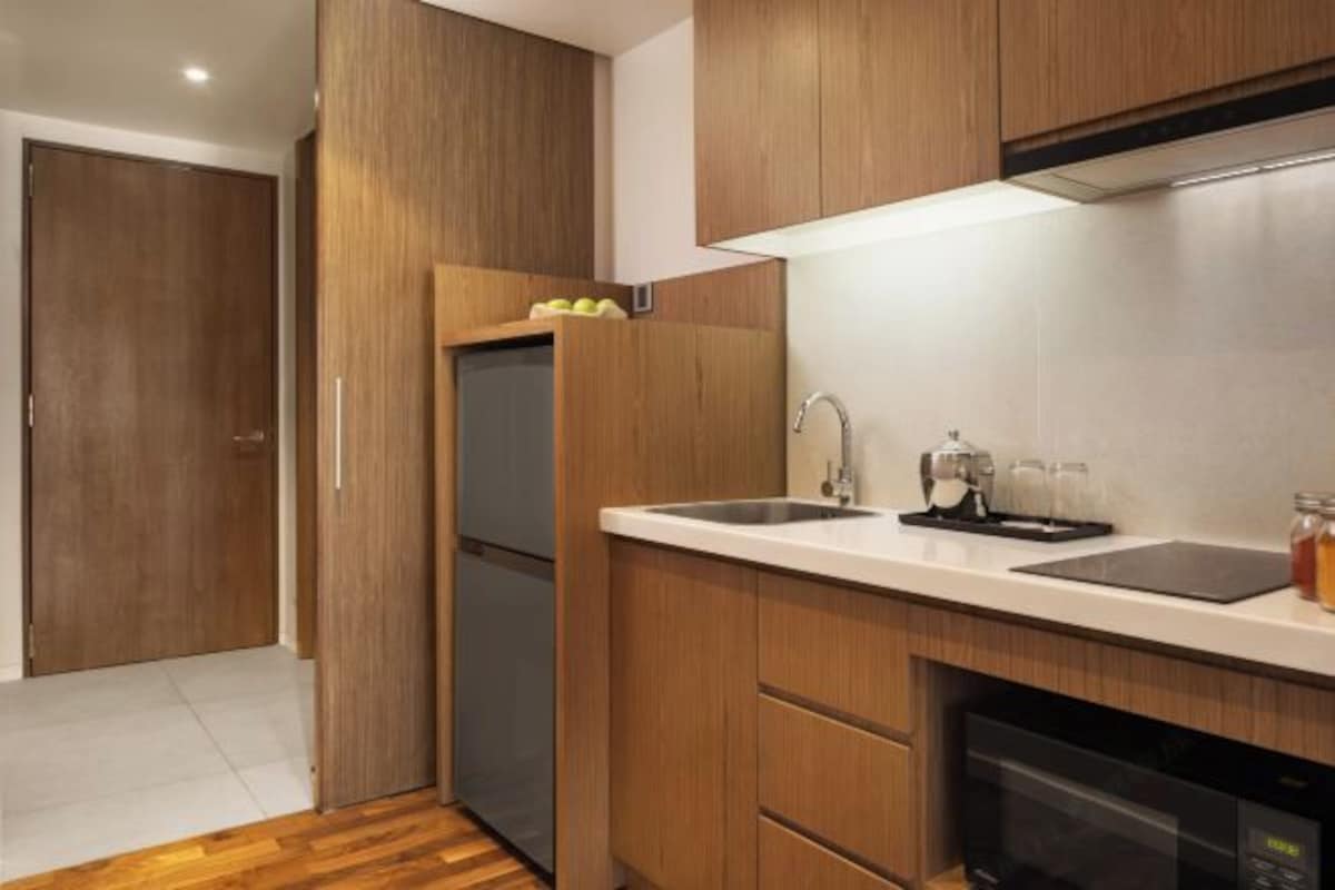 Una cocina moderna con armarios de madera, un lavamanos de acero inoxidable y un horno empotrado.