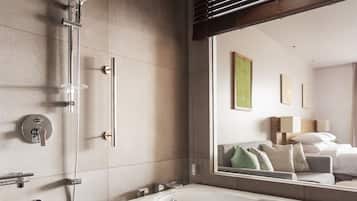 Une salle de bain moderne avec un grand miroir, une douche à l’italienne et une baignoire.